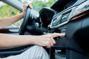 Woman sitting in a car and touch play finger in a auto smart system.