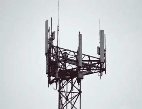Telecom tower with multiple cellular antennas against a pale sky