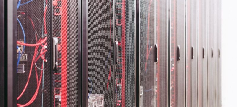 Rows of network server racks with red and blue cables in a data center